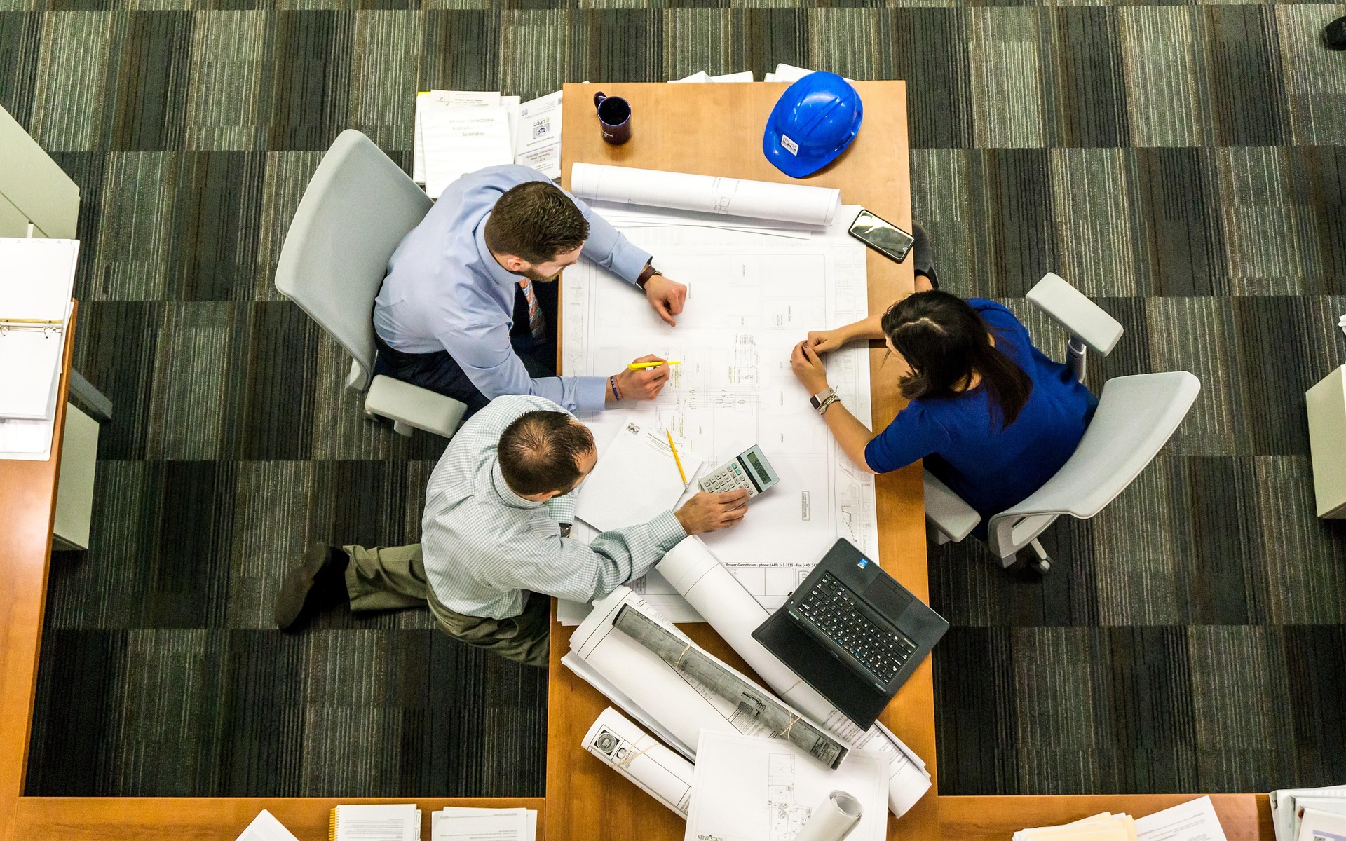 オフィスで話し合いながら業務を進めている人たち